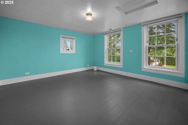 empty room featuring baseboards, visible vents, ornamental molding, and wood finished floors