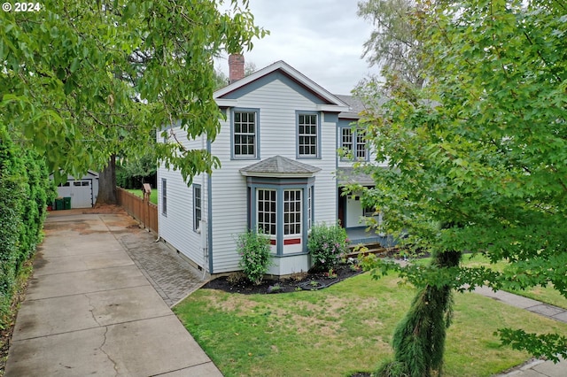 view of front of house featuring a front lawn and a shed