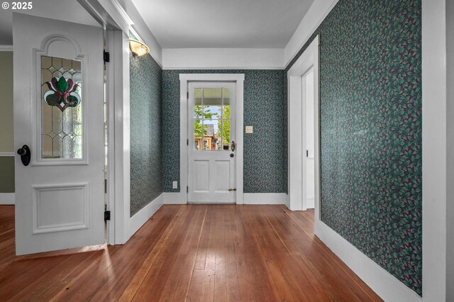 unfurnished living room featuring baseboards, a wood stove, crown molding, and hardwood / wood-style floors