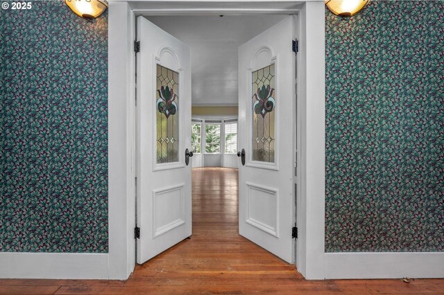 unfurnished living room with baseboards, ornamental molding, wood-type flooring, and a wood stove