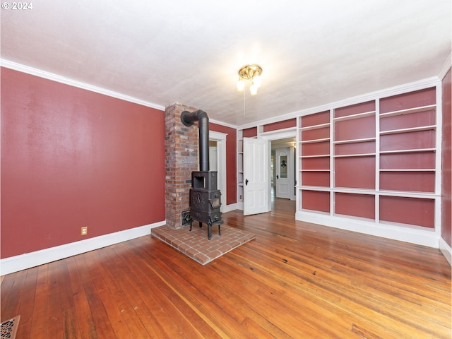 unfurnished living room featuring wood-type flooring, ornamental molding, a wood stove, and built in features