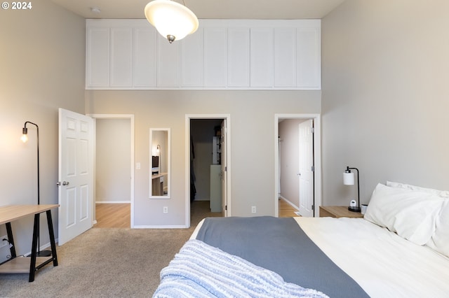 bedroom with light carpet, a spacious closet, baseboards, and a towering ceiling