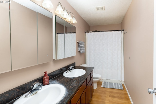 bathroom featuring visible vents, a sink, a textured ceiling, and wood finished floors