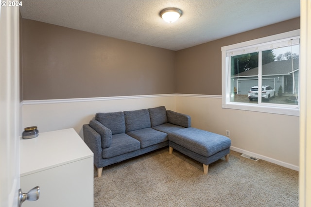 living room with carpet floors, visible vents, a textured ceiling, and baseboards