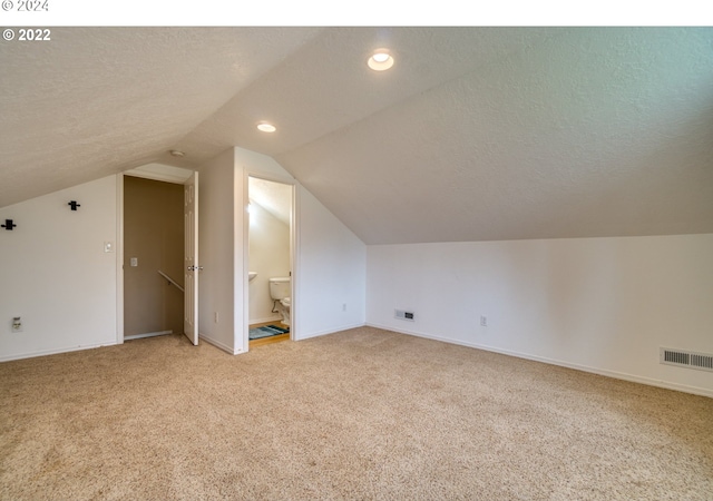 bonus room featuring light carpet, visible vents, and a textured ceiling