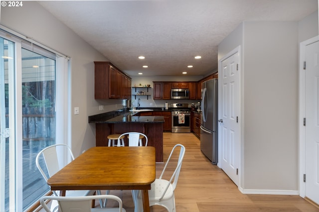 kitchen with recessed lighting, appliances with stainless steel finishes, a sink, light wood-type flooring, and a peninsula