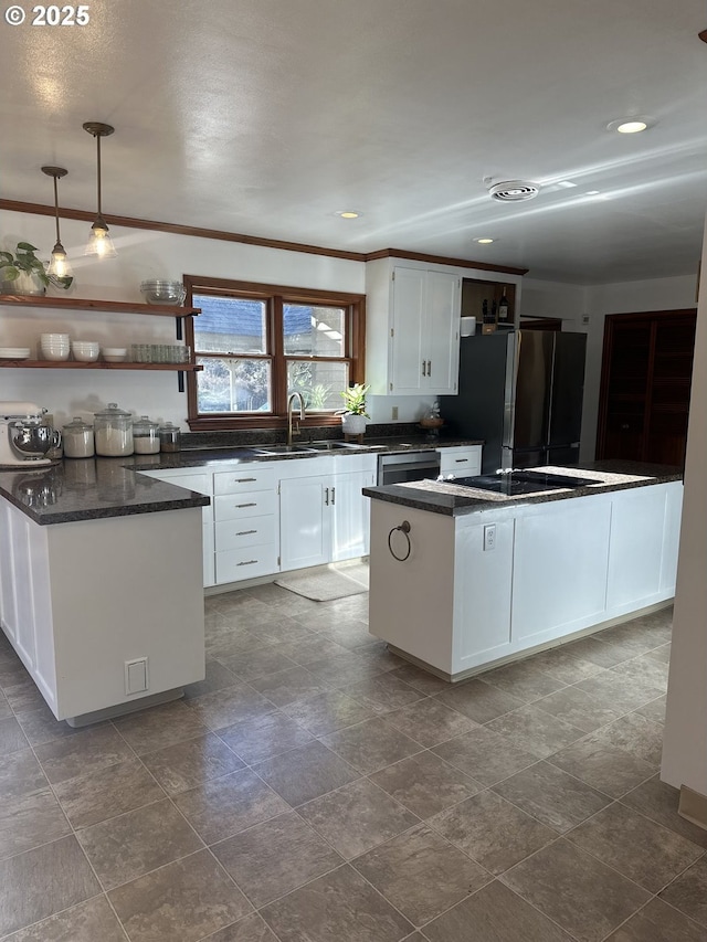 kitchen with sink, a center island, white cabinetry, hanging light fixtures, and stainless steel refrigerator