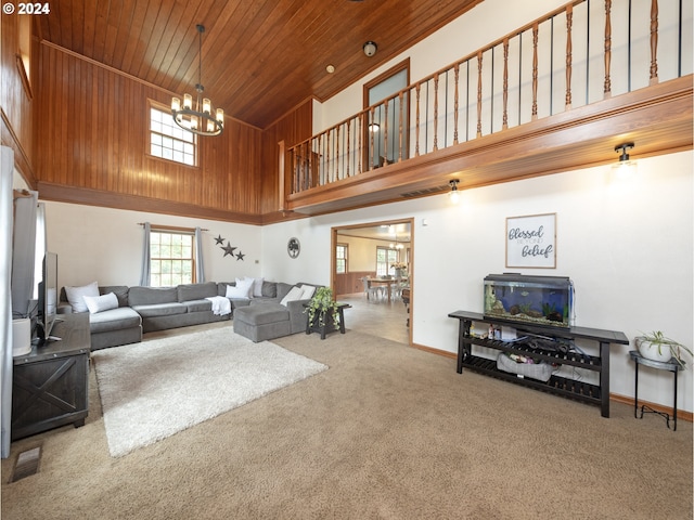 carpeted living room featuring a towering ceiling, an inviting chandelier, and wood ceiling