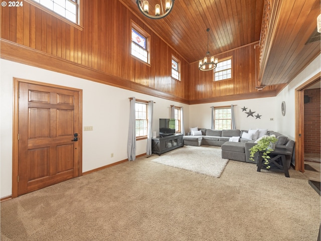 unfurnished living room with carpet flooring, a towering ceiling, a chandelier, and wood ceiling