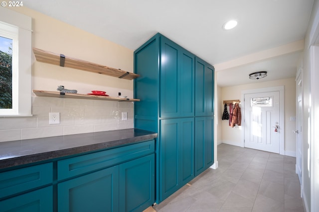 kitchen featuring backsplash, light tile patterned floors, and blue cabinets