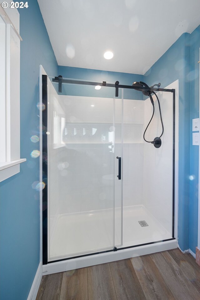 bathroom with hardwood / wood-style floors and a shower with shower door