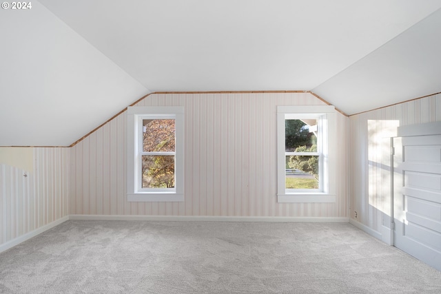 bonus room with light colored carpet, a healthy amount of sunlight, and lofted ceiling