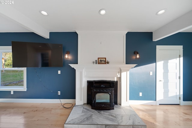 living room with beam ceiling, a wood stove, and light hardwood / wood-style flooring