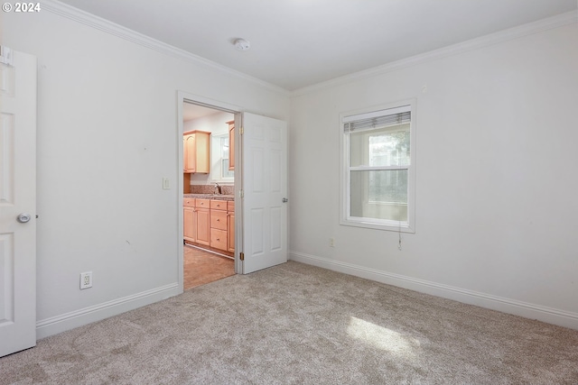 unfurnished bedroom with connected bathroom, light carpet, crown molding, and sink