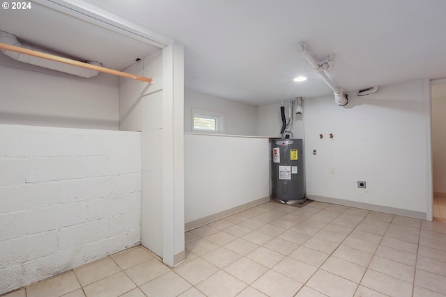 basement with electric water heater and light tile patterned floors