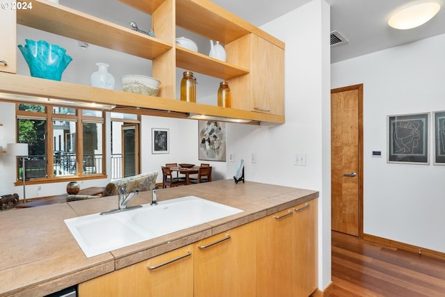 kitchen featuring hardwood / wood-style floors, sink, and tile countertops