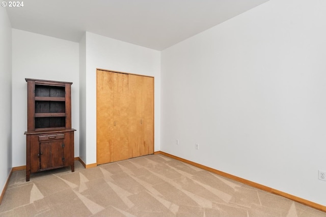 unfurnished bedroom featuring light carpet and a closet