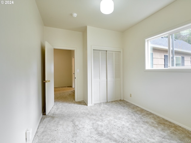 unfurnished bedroom with a closet and light colored carpet