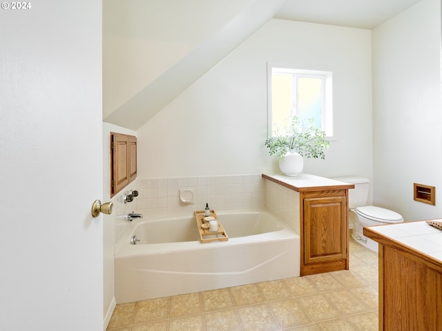 bathroom featuring vaulted ceiling, toilet, vanity, a tub to relax in, and tile patterned floors