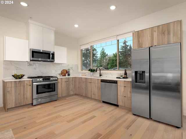 kitchen with sink, stainless steel appliances, light hardwood / wood-style floors, decorative backsplash, and white cabinets