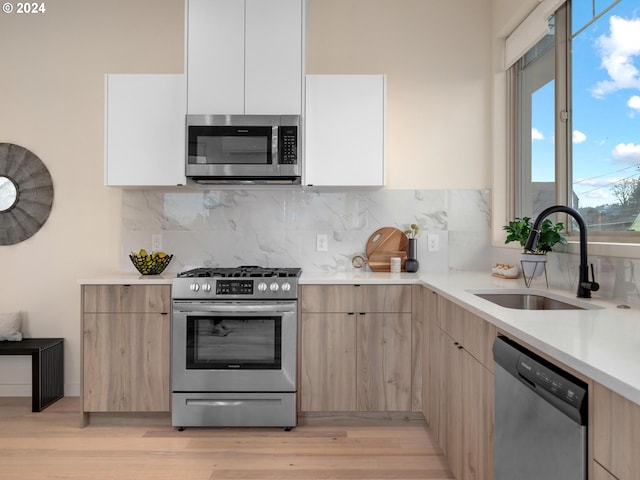 kitchen featuring appliances with stainless steel finishes, light hardwood / wood-style floors, a wealth of natural light, and sink