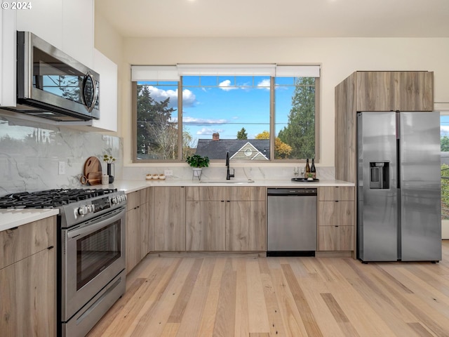 kitchen with sink, light wood-type flooring, stainless steel appliances, and tasteful backsplash