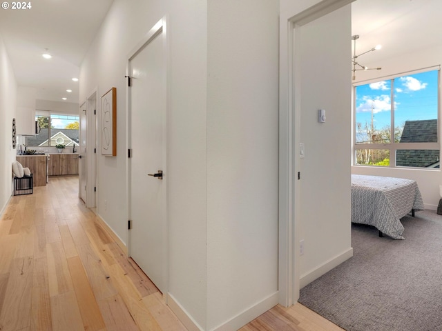 hall with light hardwood / wood-style floors and a notable chandelier