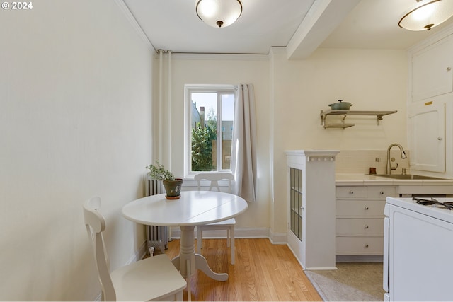 dining room with sink, crown molding, and light wood-type flooring