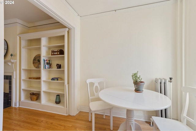 dining room featuring light hardwood / wood-style floors, radiator, built in shelves, and crown molding