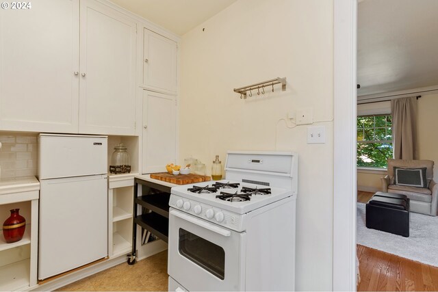 kitchen featuring white cabinetry, light wood-type flooring, tasteful backsplash, and white appliances