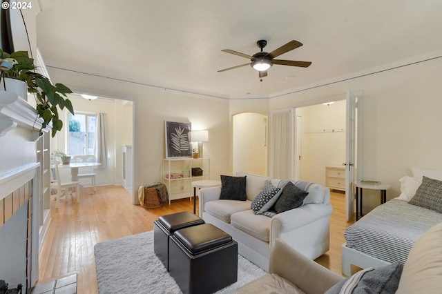 living room with a tiled fireplace, light hardwood / wood-style flooring, and ceiling fan