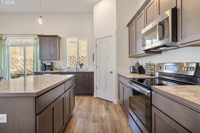 kitchen featuring light wood-type flooring, appliances with stainless steel finishes, a healthy amount of sunlight, and decorative light fixtures