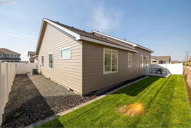 view of side of home with central AC, a lawn, and a patio