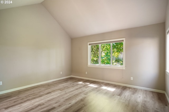 empty room featuring vaulted ceiling and light wood-type flooring