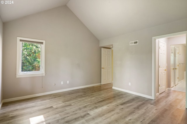 unfurnished room with high vaulted ceiling and light wood-type flooring