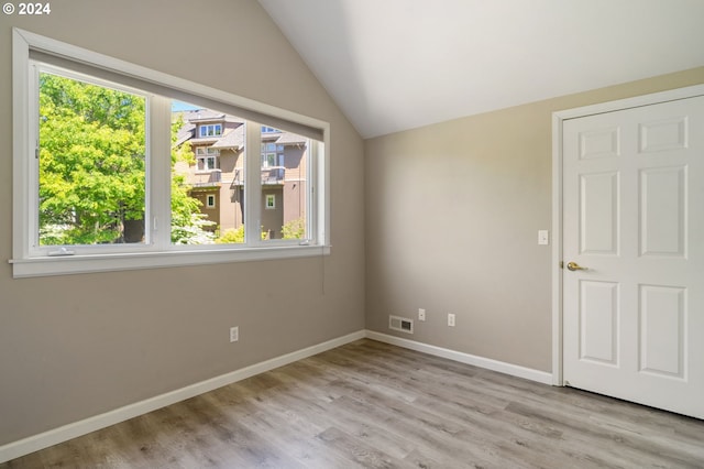 interior space featuring vaulted ceiling, hardwood / wood-style floors, and multiple windows