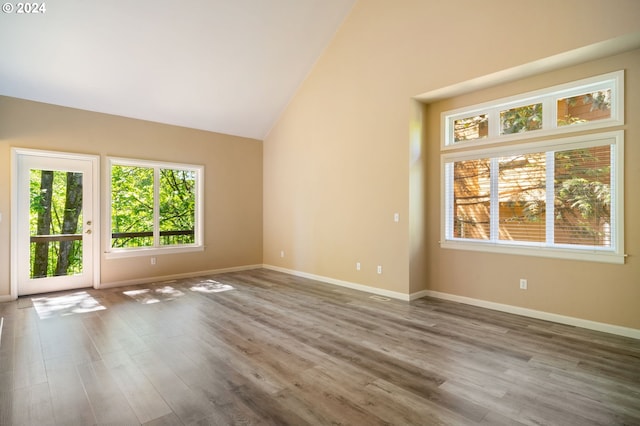 empty room with high vaulted ceiling and hardwood / wood-style floors