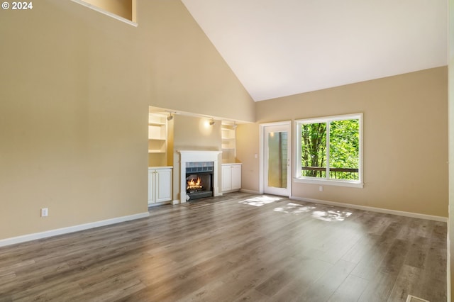 unfurnished living room featuring high vaulted ceiling, a tiled fireplace, and hardwood / wood-style flooring