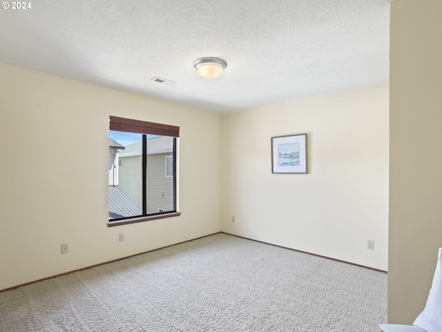 carpeted spare room featuring a textured ceiling