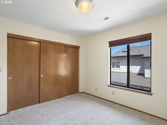 unfurnished bedroom with carpet floors, a textured ceiling, and a closet