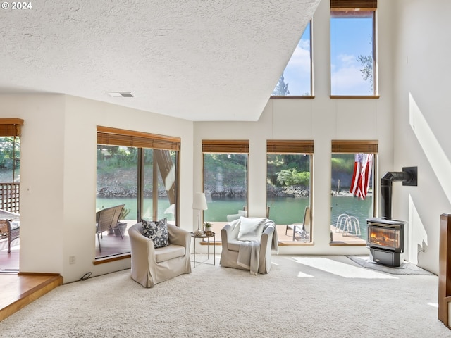 sunroom featuring a water view, a wood stove, and a wealth of natural light