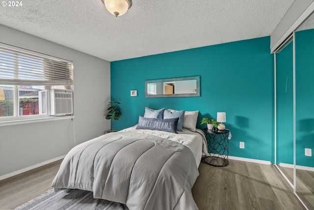 bedroom with a textured ceiling, wood-type flooring, and a closet