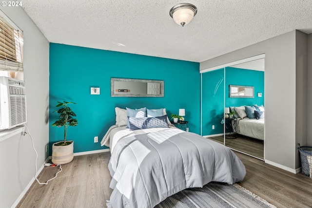 bedroom with a closet, wood-type flooring, and a textured ceiling