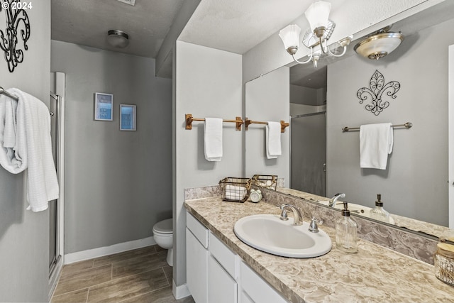 bathroom featuring a shower with door, wood-type flooring, a textured ceiling, toilet, and vanity