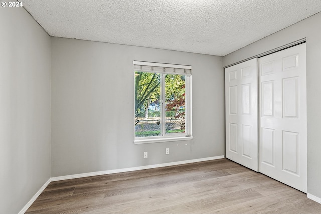 unfurnished bedroom featuring a closet, a textured ceiling, and light wood-type flooring