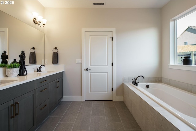 bathroom featuring vanity, tiled tub, and tile patterned flooring