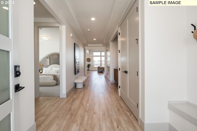 hall with light wood-type flooring and a textured ceiling