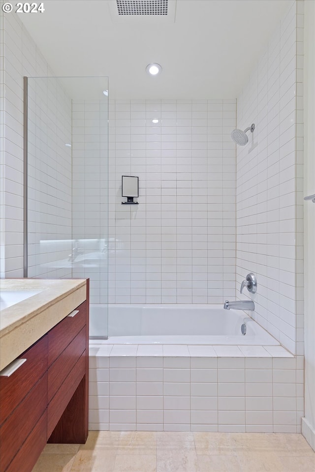 bathroom with tile patterned floors, tiled shower / bath combo, tile walls, and vanity