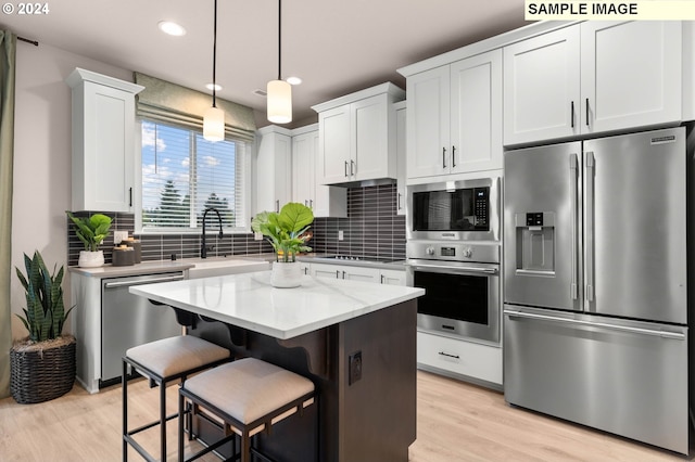 kitchen with white cabinets, appliances with stainless steel finishes, a center island, and decorative backsplash