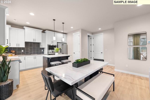 kitchen with decorative light fixtures, a center island, light hardwood / wood-style floors, and appliances with stainless steel finishes